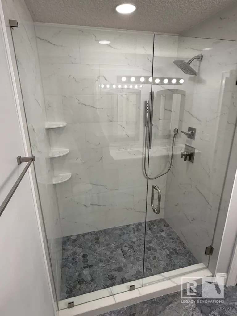 Close-up of a glass shower enclosure with a rainfall showerhead and marble-style tile in Autumn Green, Jacksonville, FL.