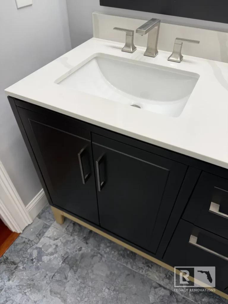 Elegant bathroom vanity with a white countertop, black cabinetry, and sleek silver faucet in Autumn Green, Jacksonville, FL.
