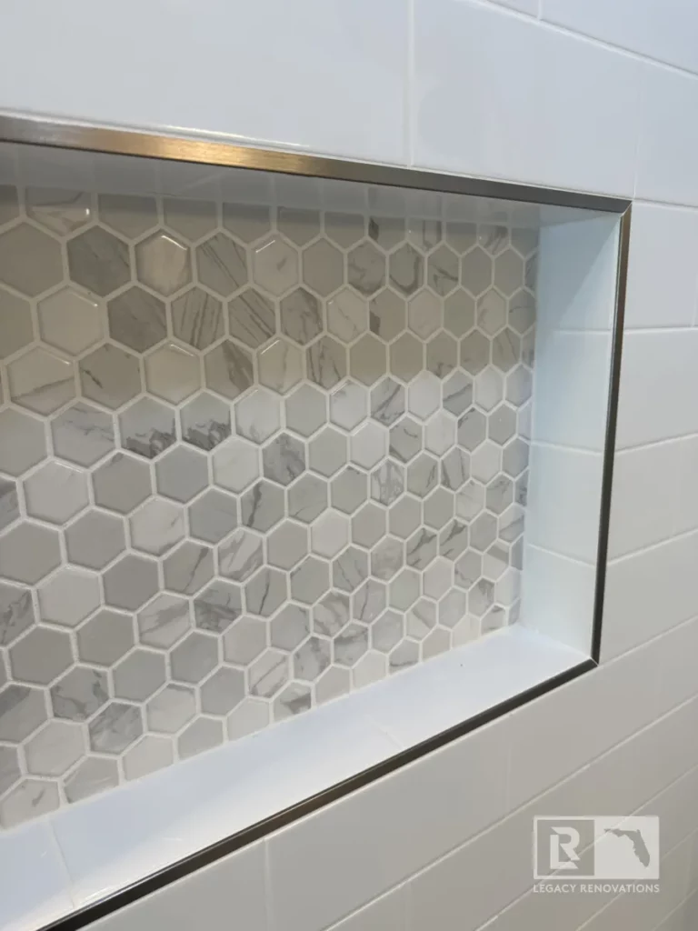 beautifully tiled shower featuring timeless white subway tiles and a built-in niche with decorative hexagonal mosaic tiles.