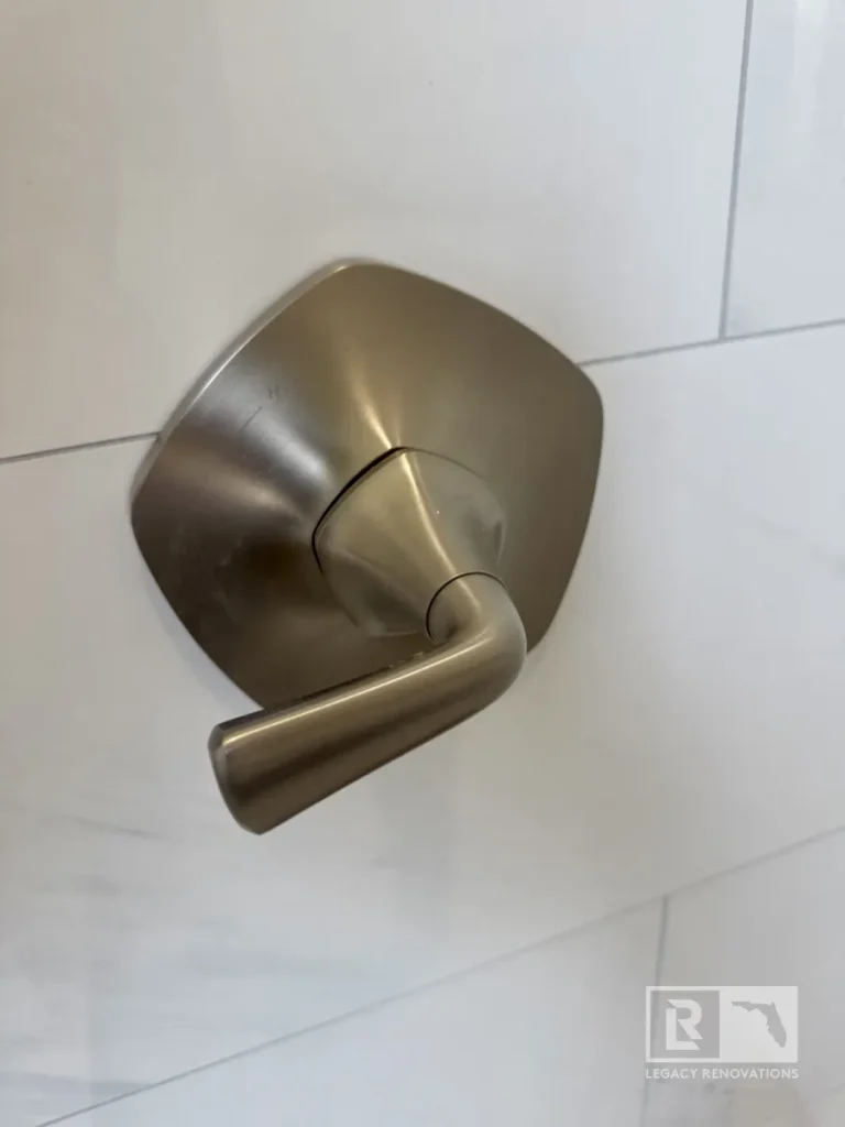 Close-up of a brushed nickel shower valve handle installed on large-format marble-look tile in a Jacksonville, FL bathroom remodel.