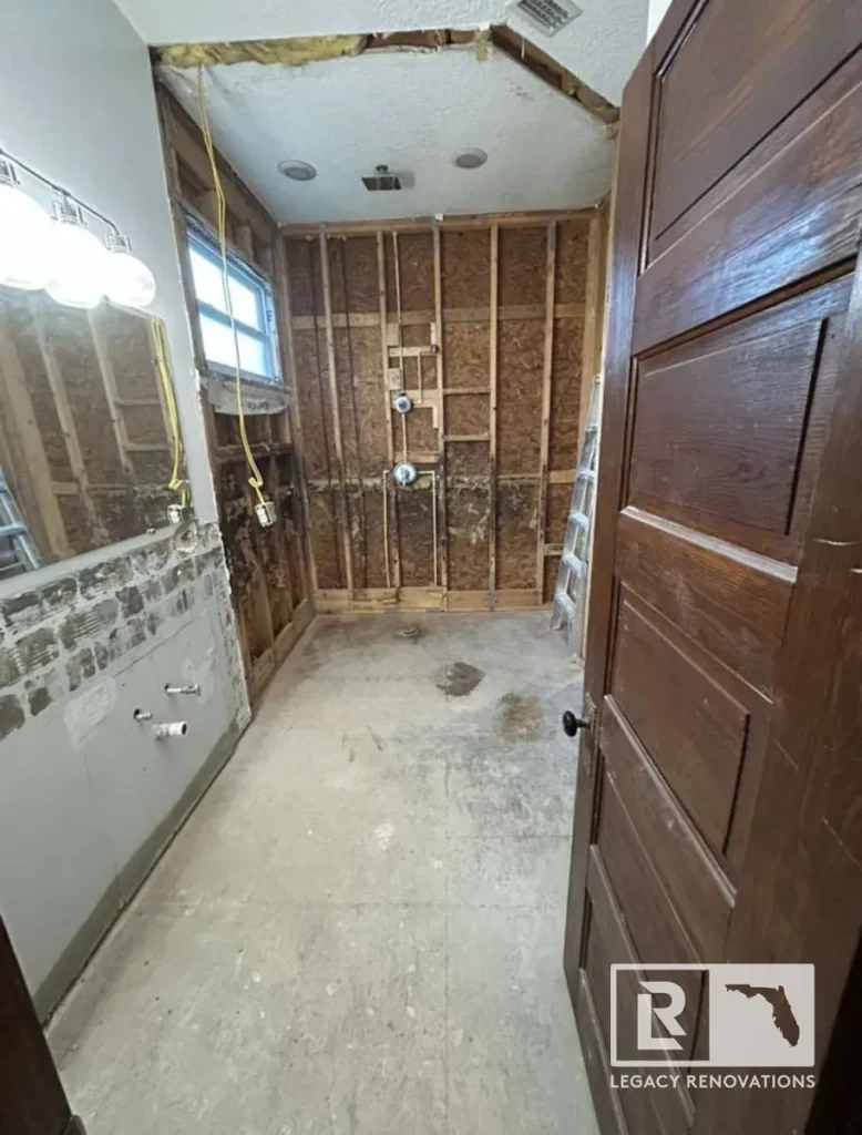 Bathroom remodel demolition showing exposed wall framing, plumbing, and subfloor during renovation in Jacksonville, FL.