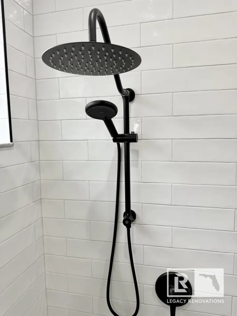 Matte black dual rainfall shower head and handheld wand set against white subway tile in a Jacksonville, FL shower renovation.