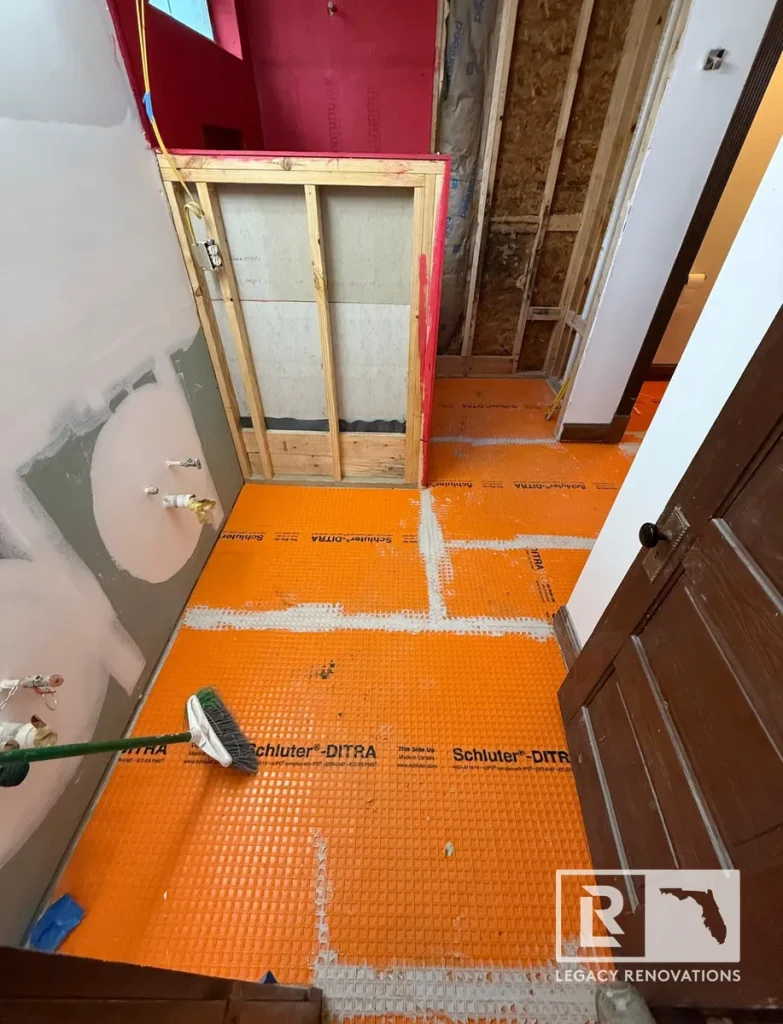 Bathroom floor under construction with Schluter DITRA uncoupling membrane installed before tile installation.