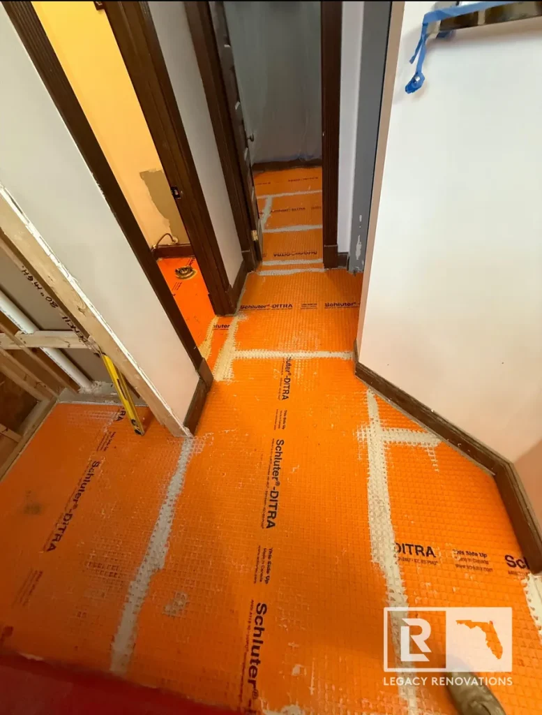 Schluter DITRA uncoupling membrane installed throughout a bathroom floor before porcelain tile installation.