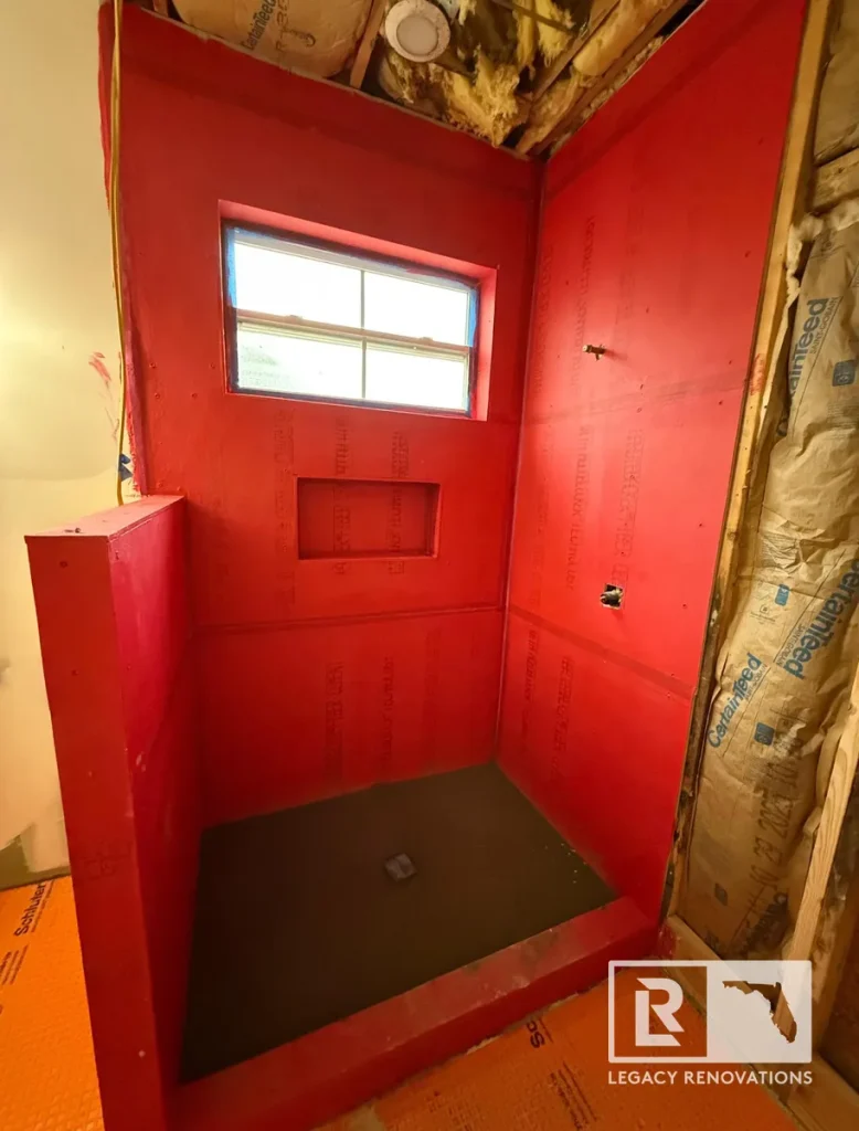 Custom walk-in shower with a waterproof membrane, sloped shower pan, and recessed niche during bathroom renovation.