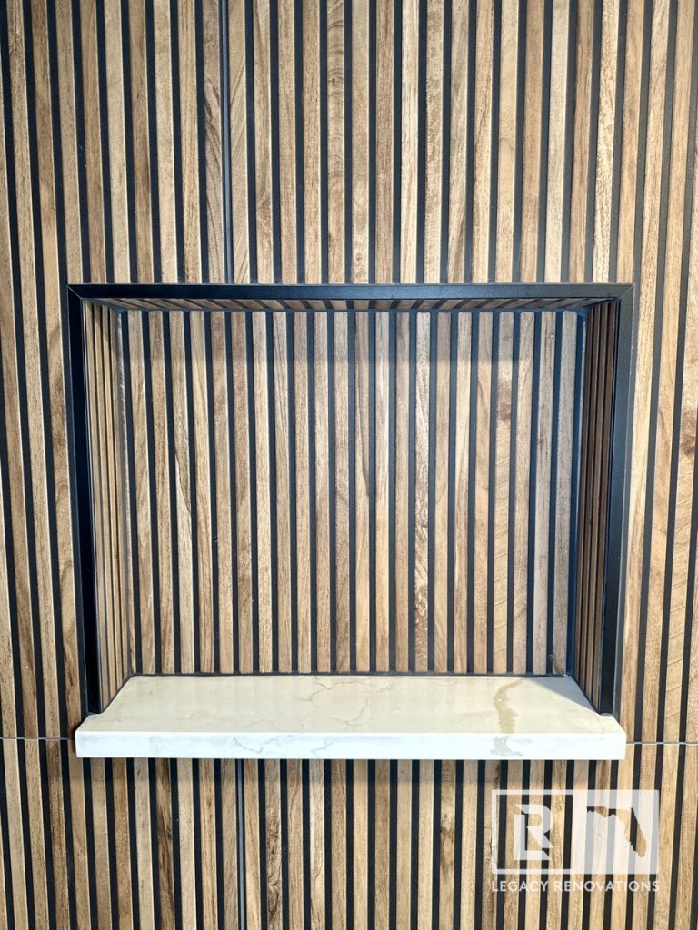 Decorative shower niche with black trim and fluted tile wall in Jacksonville, FL.