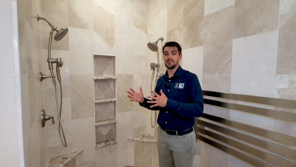 Luxury primary bathroom with a custom walk-in shower, large-format tile, built-in shelving, dual shower heads, and heated towel rack.