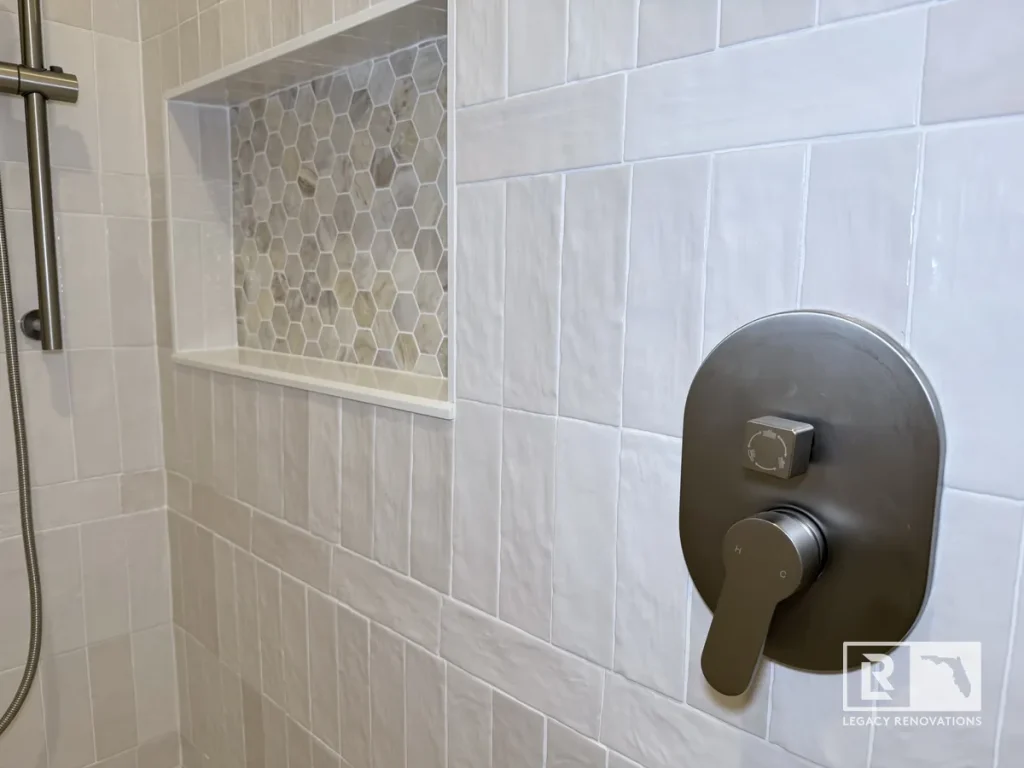 Brushed nickel shower control valve handle installed on an off-white tile wall in a Mandarin Jacksonville FL residence.