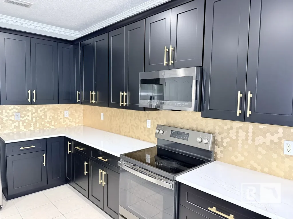 Stainless steel electric range and microwave flanked by dark cabinets and a hexagon tile wall.