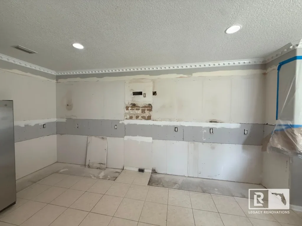 Bare drywall wall with electrical outlet cutouts and unpainted joint compound in an empty kitchen.