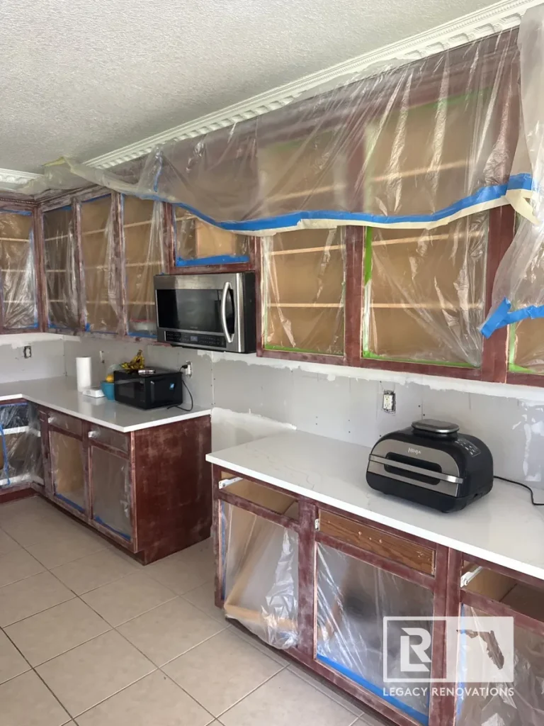 Wooden kitchen cabinet frames masked with plastic film and blue tape before painting.