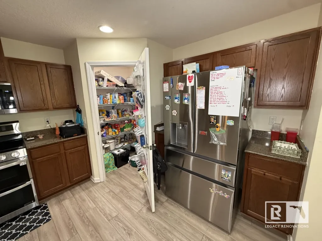 Dark oak kitchen cabinets with stainless steel refrigerator and open walk-in wire shelf pantry in a Jacksonville FL home.