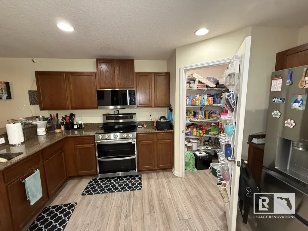 Wide shot of a Jacksonville FL home kitchen showing brown wooden cabinets, stainless steel double oven stove, and open walk-in pantry.